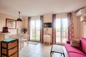 salon z różową kanapą i stołem w obiekcie Les Coteaux de Pont Royal en Provence - maeva Home - Appartement 2 Pièces 4 Personnes - Prestige MAE-6030 w mieście Mallemort
