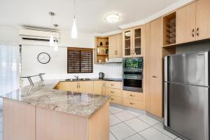 cocina con armarios de madera y nevera de acero inoxidable en Meridien Beachfront Apartments at Trinity Beach, en Trinity Beach