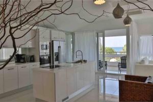 a kitchen with white cabinets and a tree branch hanging from the ceiling at Beach Apartment with Seaview II in Olympic Beach