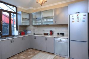  La cuisine est équipée de placards blancs et d'un réfrigérateur. dans l'établissement Syune Mini Hotel, à Gyumri