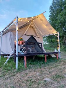 une tente éclairée dans un champ dans l'établissement Aimasas Camping, à Lielie Unguri