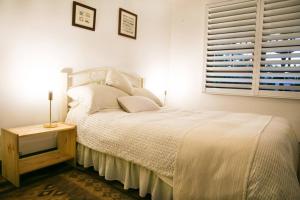 a bedroom with a white bed and a window at Luxury Pumicestone Cottage - Beach Charm - ZA7 in Golden Beach