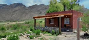 a small house in a field with mountains in the background at Fincachica in Cachí