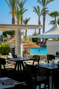 a restaurant with tables and chairs and a swimming pool at Tasia Maris Beach Hotel - Adults Only in Ayia Napa