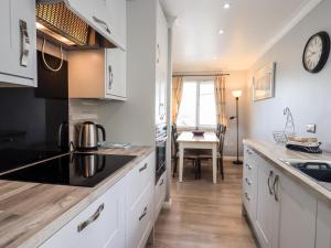 a kitchen with white cabinets and a table with a clock at Fairview in Bowness-on-Windermere
