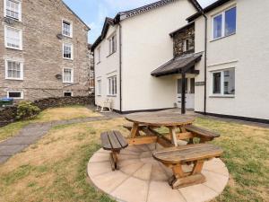 a wooden picnic table and two benches in a yard at Fairview in Bowness-on-Windermere