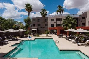 uma piscina num hotel com cadeiras e guarda-sóis em Courtyard Scottsdale North em Scottsdale