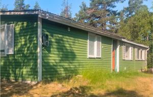 una casa verde con ventanas blancas en el lateral. en Lovely Home In Mnsters With Kitchen, en Mönsterås