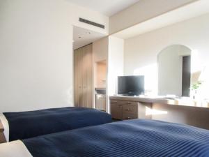 a bedroom with a bed and a desk with a tv at HOTEL LiVEMAX BUDGET SAPPORO in Sapporo