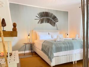 a bedroom with a white bed with a palm leaf on the wall at Boho Style Apartment - Messe - Rüttenscheid in Essen