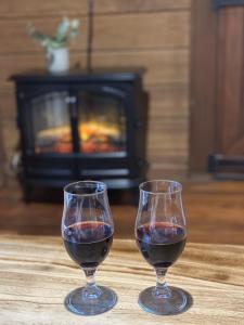 two glasses of red wine on a table with a fireplace at Koompartoo Retreat Bellingen in Bellingen