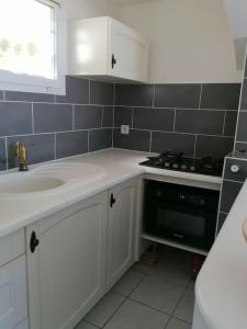 a white kitchen with a sink and a stove at Maison T3 avec vue au bord de l’étang in Istres