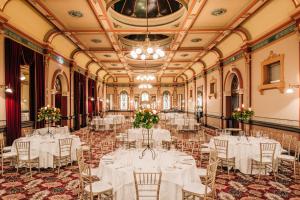um salão de banquetes com mesas e cadeiras brancas em The Hotel Windsor em Melbourne