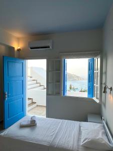 a bedroom with a bed with a blue door and a window at Hotel Petradi in Ios Chora