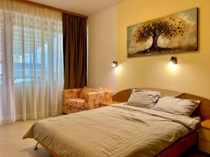 a bedroom with a bed and a chair and a window at Premium Apartment Midia Beach in Sunny Beach