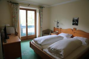 una camera da letto con due letti, una scrivania e una finestra di Hotel Voglauerhof ad Abtenau