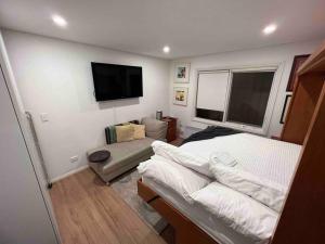 Private 1 bedroom apartment near beach and shops في سيدني: غرفة نوم بسرير وتلفزيون بشاشة مسطحة