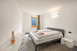 Dormitorio blanco con cama y mesa en Appartamento Borgo Pastoedo - Happy Rentals en Tenno