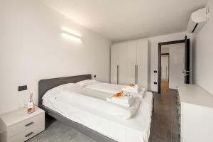 1 dormitorio blanco con 1 cama grande con sábanas blancas en Appartamento Borgo Pastoedo - Happy Rentals en Tenno