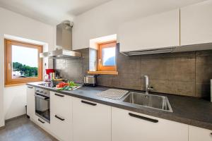 una cocina con armarios blancos y fregadero en Appartamento Borgo Pastoedo - Happy Rentals en Tenno