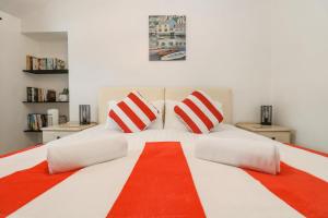 a large white bed with red and white pillows at Walter in Penzance