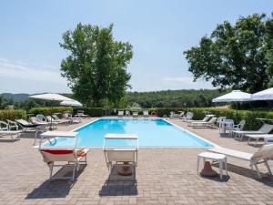 una gran piscina con sillas y sombrillas en Surrounded by the beautiful sloping Tuscan landscape, en Casole dʼElsa