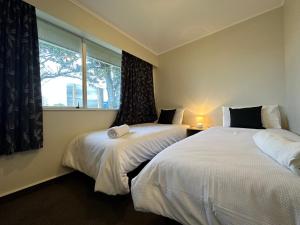two beds in a room with a window at Inner Gem On Ada in Palmerston North