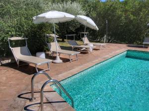 アッシジにあるPicturesque Holiday Home in Assisi with Poolのスイミングプールの隣にあるスイミングプール(椅子、パラソル付)