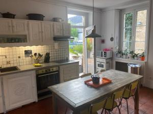 uma cozinha com armários brancos e uma mesa com cadeiras em VILLA MARLISE Chambre Hôtes em Saint-Satur