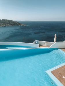a blue swimming pool with a view of the ocean at Hotel Petradi in Ios Chora