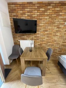 a dining room table with chairs and a tv on a brick wall at Route 7 Rooms in Myślenice