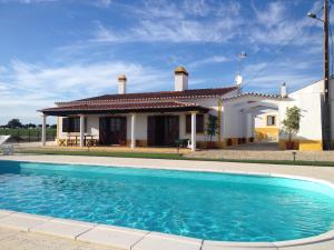 a villa with a swimming pool in front of a house at Agro-Turismo do ROXO in Santa Vitória