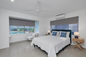 a white bedroom with a bed and a chair at Endeavour Holiday House Clifton Beach in Clifton Beach