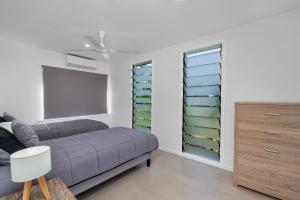 a bedroom with a purple bed and green shelves at Endeavour Holiday House Clifton Beach in Clifton Beach