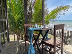 een tafel en stoelen op een veranda met het strand bij AYNI in Canoas