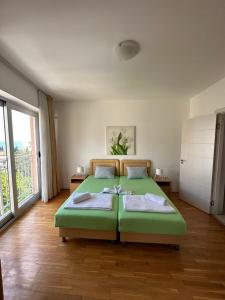a bedroom with a green bed and a large window at Apartments Mitende in Budva