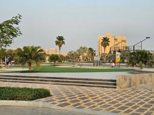 een park met een speeltuin met palmbomen en gebouwen bij Luxury see view studio Al Marjan in Ras al Khaimah