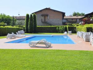 una piscina con sillas blancas y una casa en Vibrant Holiday Home in Lazise with Swimming Pool near 2 Lakes, en Lazise