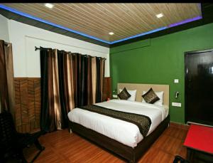 a bedroom with a bed with a green wall at Hotel Great Nainital in Nainital