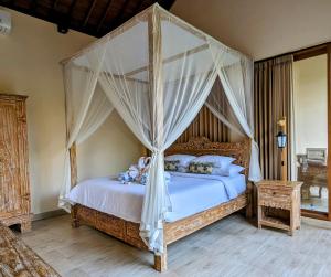 een slaapkamer met een hemelbed met witte lakens en kussens bij Villa Ulun Mertha - 1BR Private Villa in Ubud