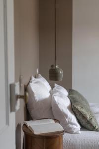 uma cama com almofadas brancas e um livro sobre uma mesa em La Maison des Monts d'Or em Saint-Germain-au-Mont-dʼOr