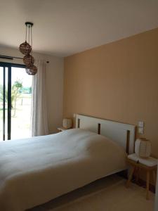 a bedroom with a white bed and a window at Maison neuve avec piscine chauffée, 4 kms de Contis plage in Saint-Julien-en-Born