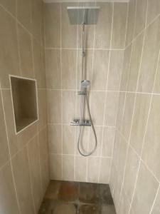 a shower with a hose in a tiled bathroom at Maison neuve avec piscine chauffée, 4 kms de Contis plage in Saint-Julien-en-Born