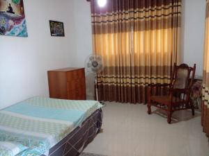 a bedroom with two beds and a chair and a window at Muthu Villa Sri Lanka in Kalutara