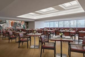 كاوتيارد باي ماريوت هونغ كونغ في هونغ كونغ: غرفة طعام مع طاولات وكراسي ونوافذ