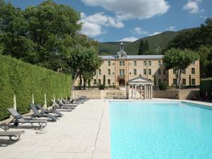 una piscina con tumbonas y un edificio en A beautiful 2 persons studio in a chateau with swimming pool, en Montbrun-les-Bains