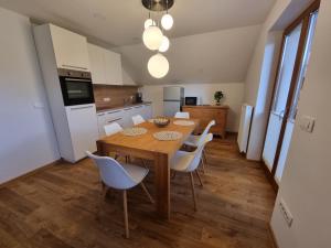 a kitchen with a wooden table and white chairs at Apartment 199 in Zgornje Gorje