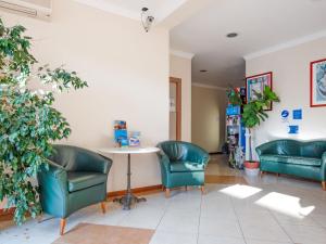 uma sala de espera com cadeiras verdes e uma mesa em Comfy Apartment near Rimini Adriatic Coast with a Sea View em Rimini