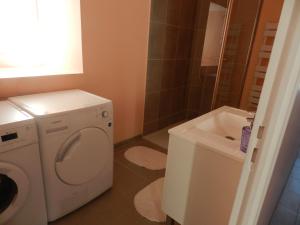 a bathroom with a washing machine and a sink at Gîte Utah in Saint-Laurent-sur-Mer