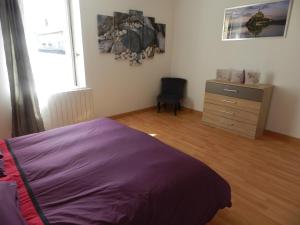 a bedroom with a purple bed and a dresser at Gîte Utah in Saint-Laurent-sur-Mer